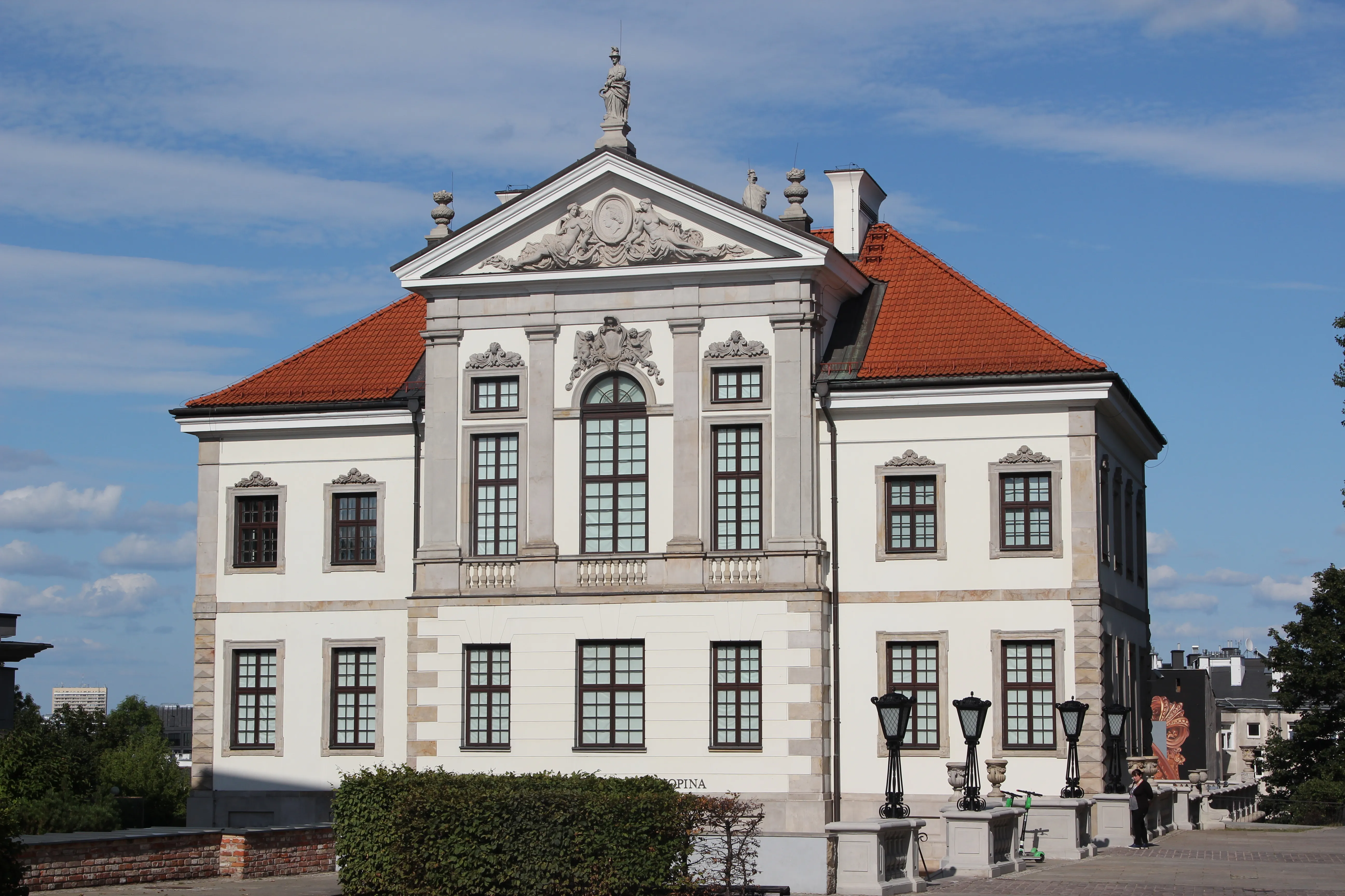 Classical white building with red-tiled roof and ornate facade under blue sky