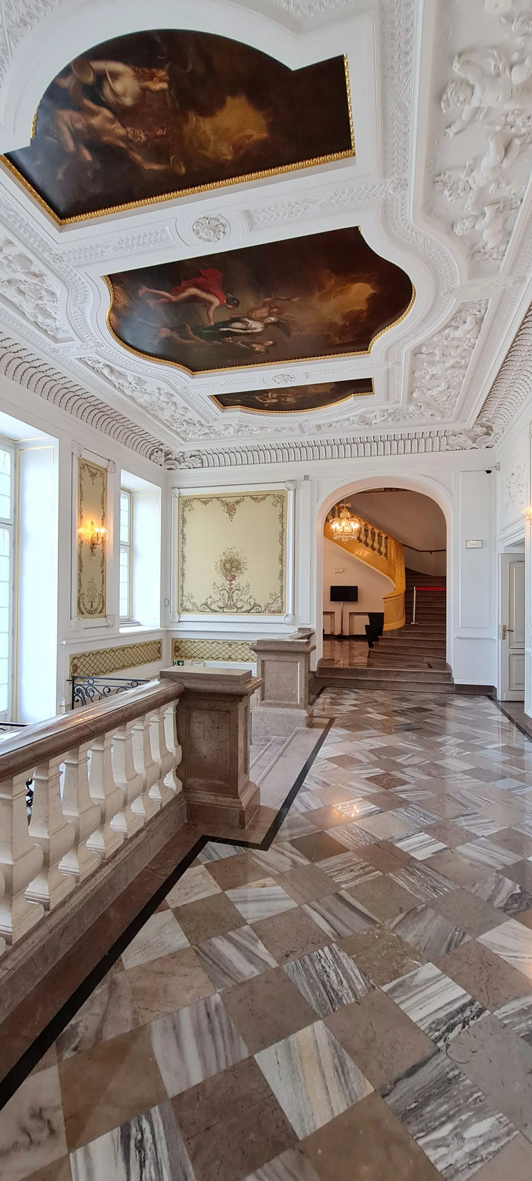Ornate hallway with marble flooring, white stucco ceilings, and large ceiling frescoes in the Fryderyk Chopin Museum