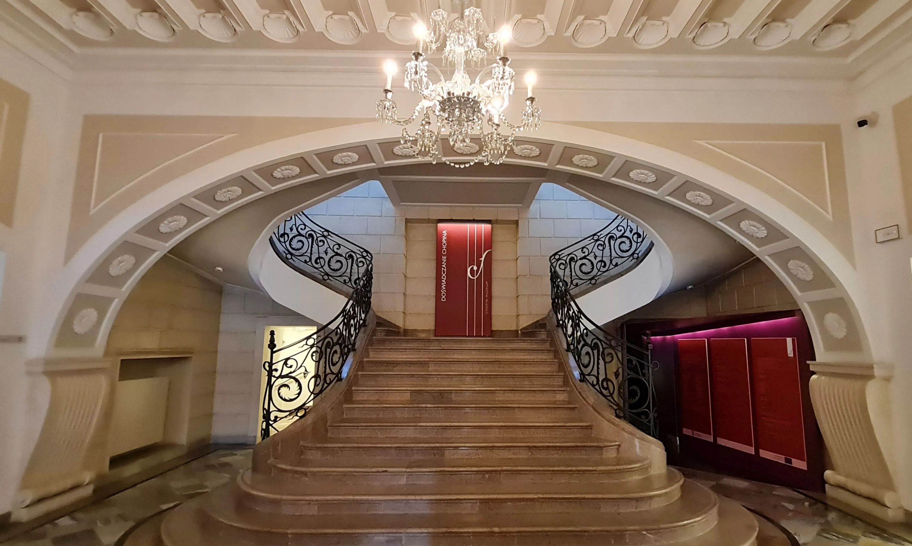 Grand staircase with ornate railings and a chandelier in the Fryderyk Chopin Museum