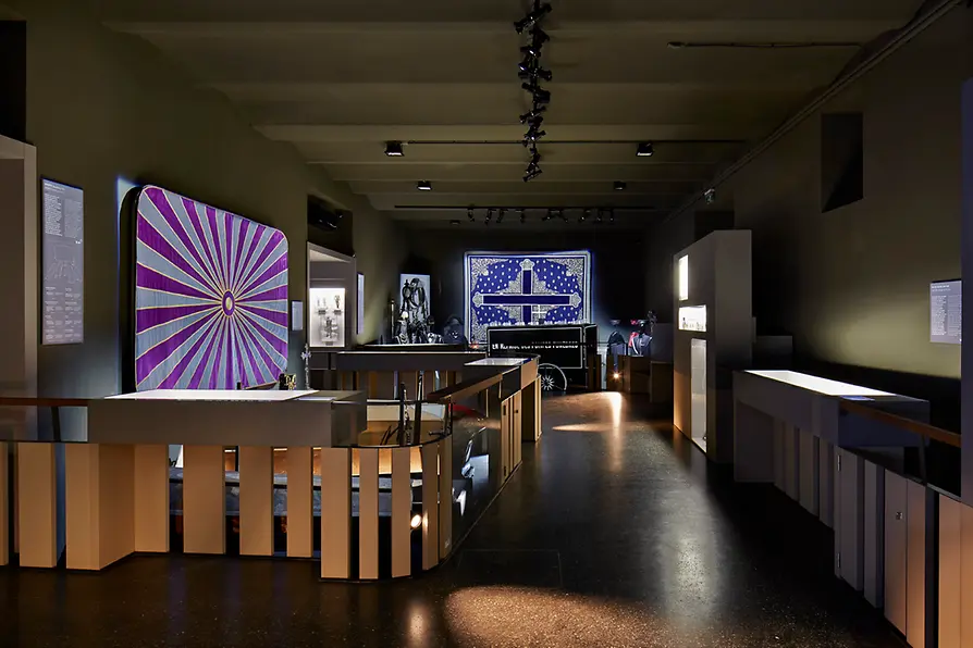 Interieur van een museumgalerij met vitrines en grote kunstwerken aan de muren