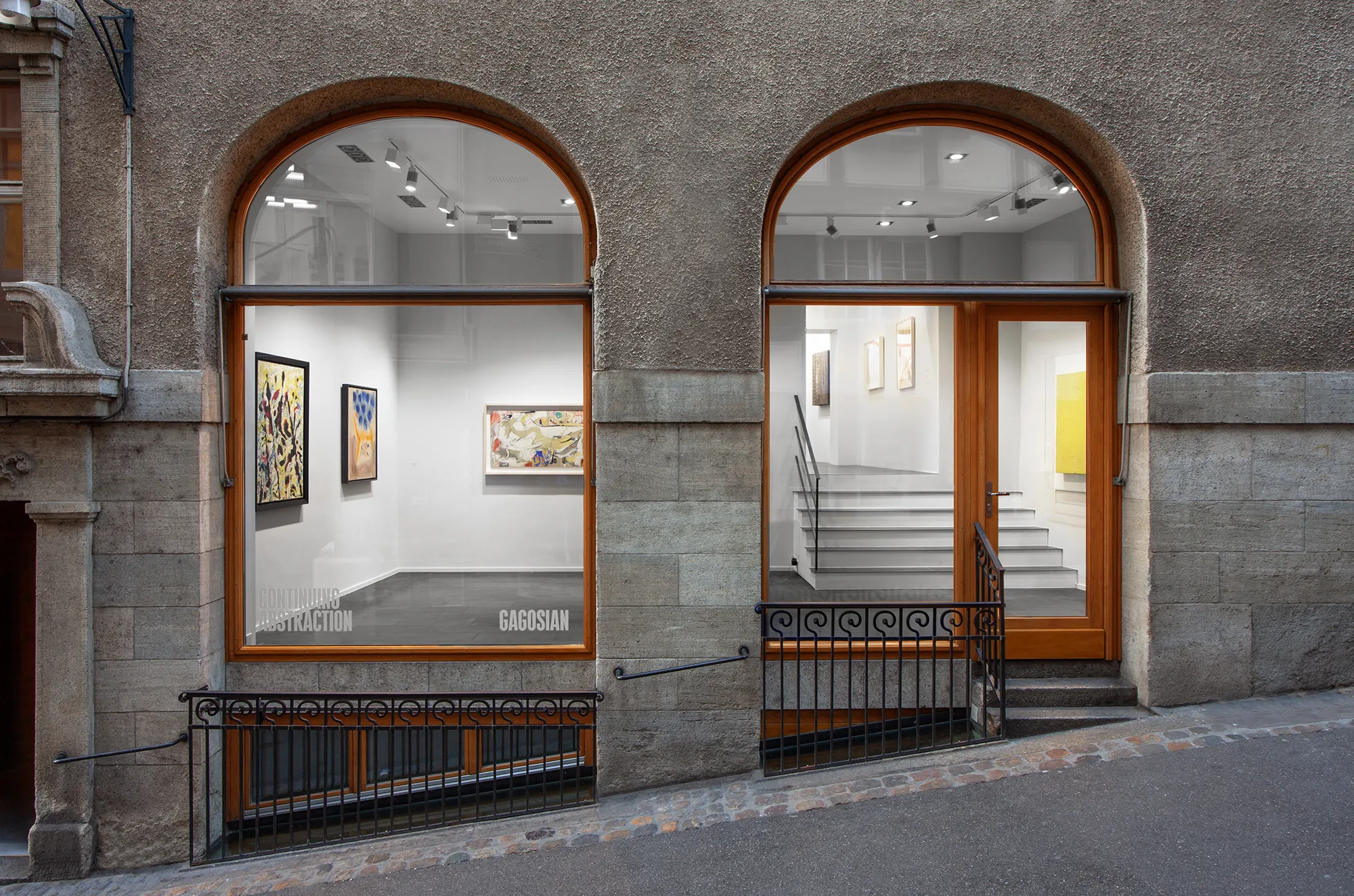 Fachada de piedra con dos grandes ventanales arqueados que revelan el interior de una galería con pinturas en paredes blancas, con el cartel de Gagosian visible en el cristal