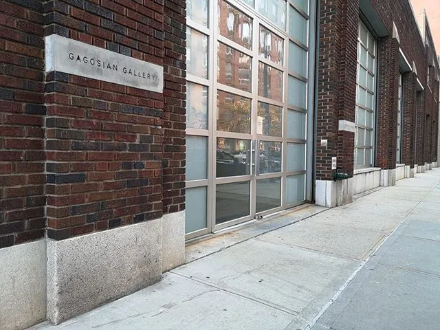 Fachada de ladrillo rojo de un edificio con una placa de piedra que dice Gagosian Gallery y grandes paneles de cristal a lo largo de una acera urbana
