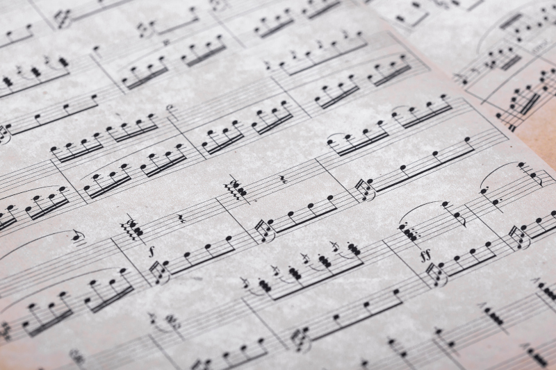 Close-up of piano roll with musical notations and perforations on aged paper