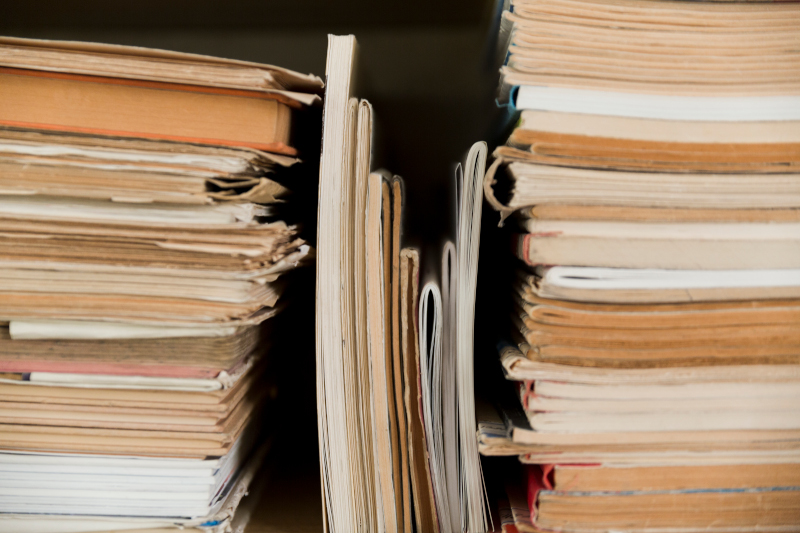 Stacks of aged paper documents with varied thickness and visible wear, tightly packed together