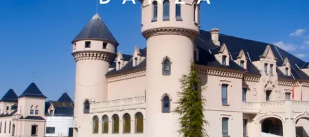 Un edificio parecido a un castillo con torretas y una fachada de color claro bajo un cielo azul