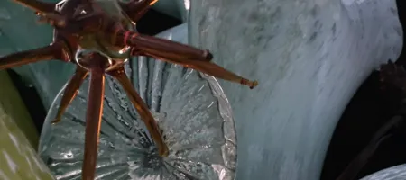 primer plano de una escultura de vidrio con brazos de color cobre y una base texturizada