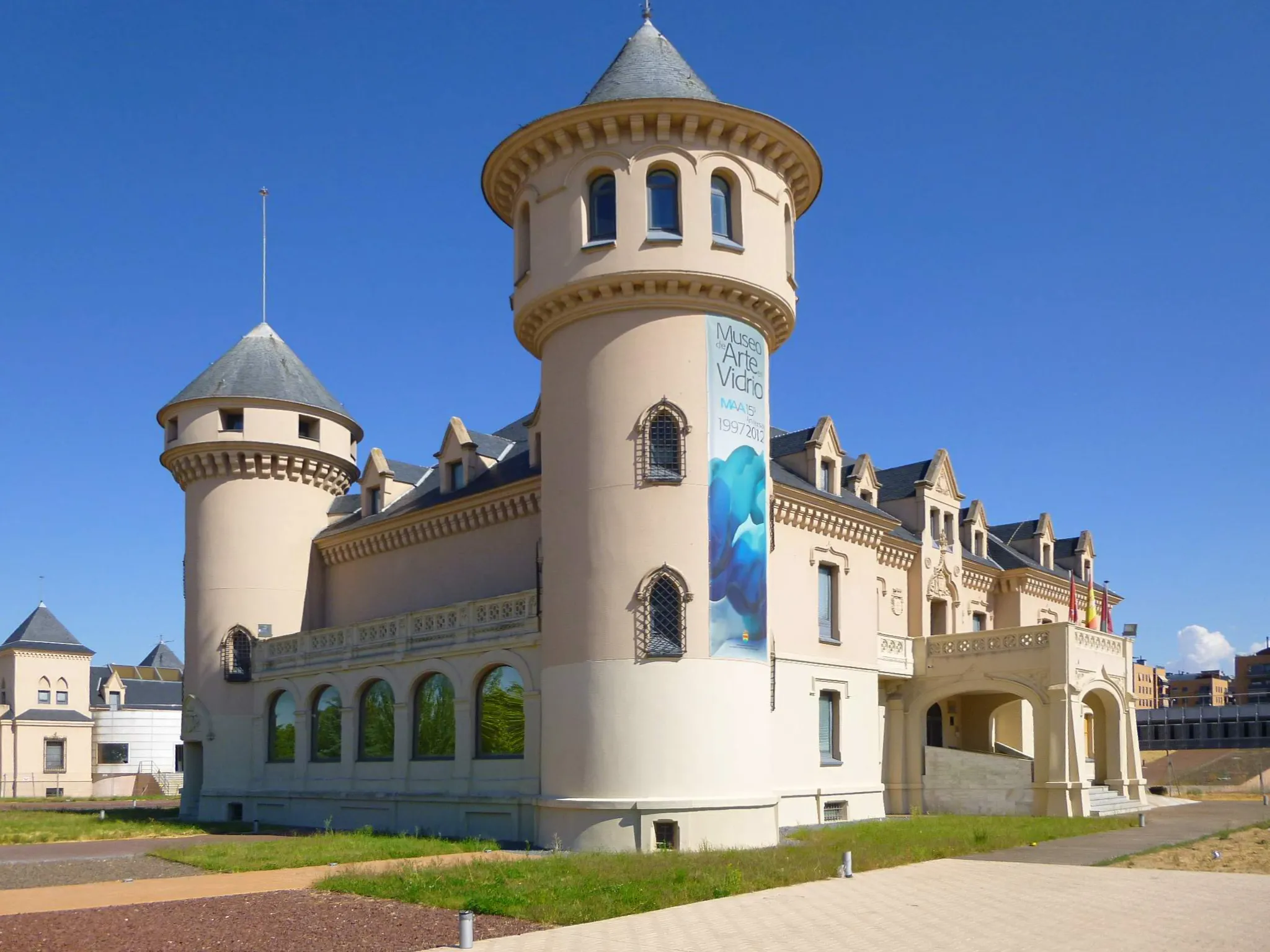 Un edificio de aspecto de castillo con torretas y ventanas arqueadas bajo un cielo azul claro