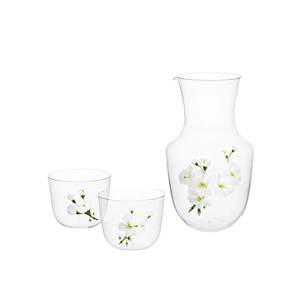 Jarra de cristal y dos vasos con motivos florales blancos