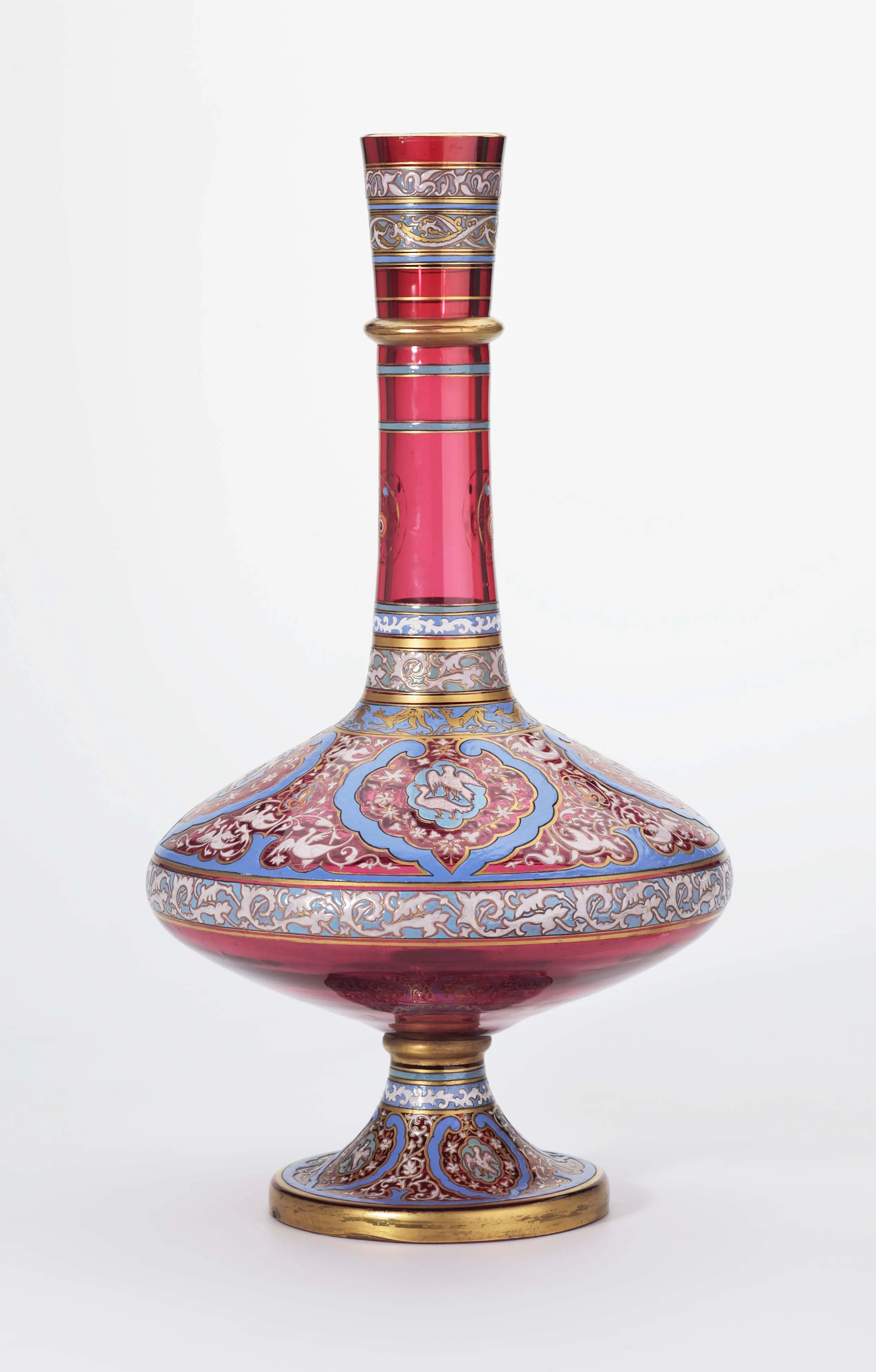 Un jarrón de cristal rojo con motivos decorativos dorados y azules sobre un fondo blanco