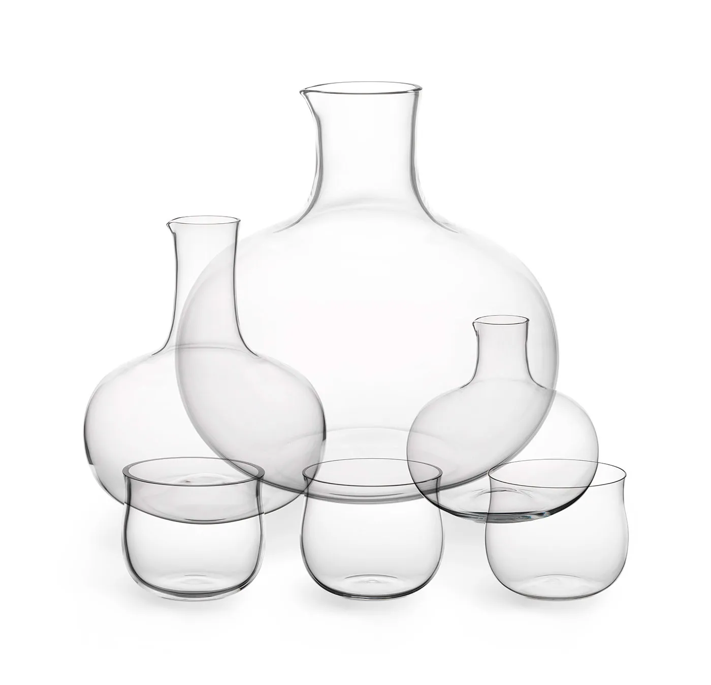 jarras de vidrio transparente y vasos dispuestos sobre una superficie blanca