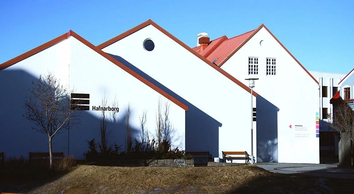 Edificio blanco con tejados a dos aguas con bordes rojos y un letrero de Hafnarborg en la pared, vista exterior del centro cultural
