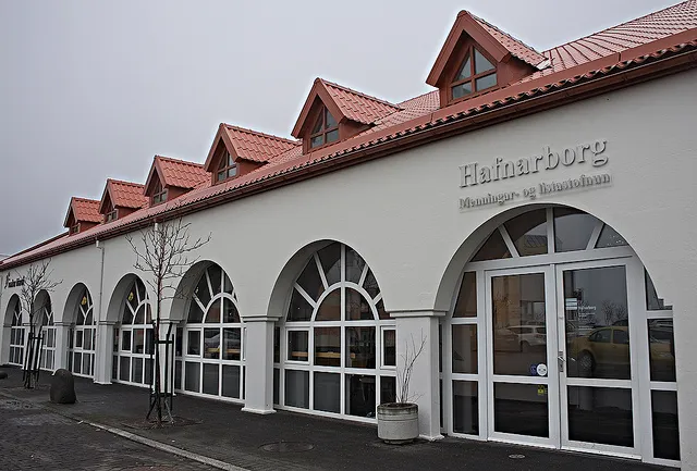 Fachada blanca con ventanas de arco y tejado de tejas rojas donde se muestra el letrero de Hafnarborg