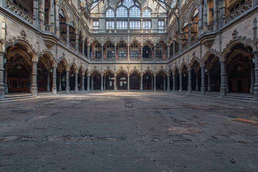 Vista interior amplia del patio neogótico de la Handelsbeurs Antwerpen con arcadas columnadas y suelo pavimentado.