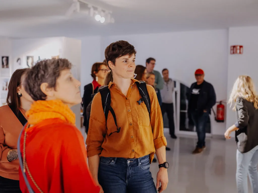 Grupo de personas en un espacio de exposición interior con paredes blancas y paneles de exhibición
