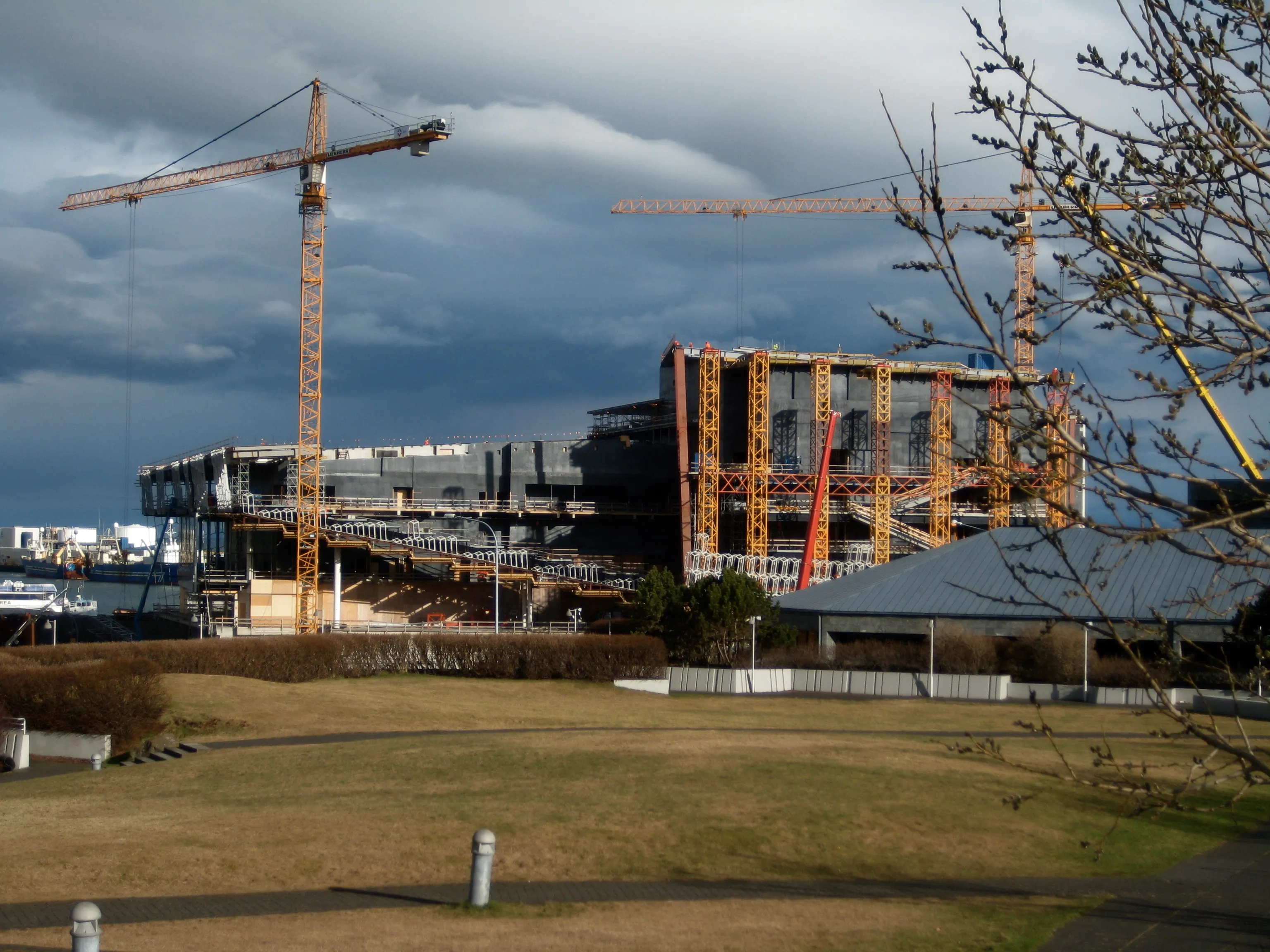 Harpa Concert Hall en construcción con altas grúas torre y estructura de acero expuesta bajo un cielo nublado