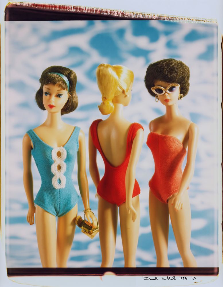 Three vintage fashion dolls in blue and red swimsuits with a wavy blue background, signed at bottom right