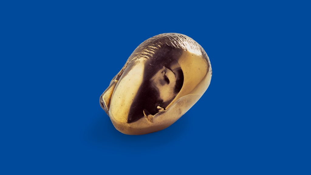 Golden abstract sculptural face on blue background, displayed as part of an art exhibition