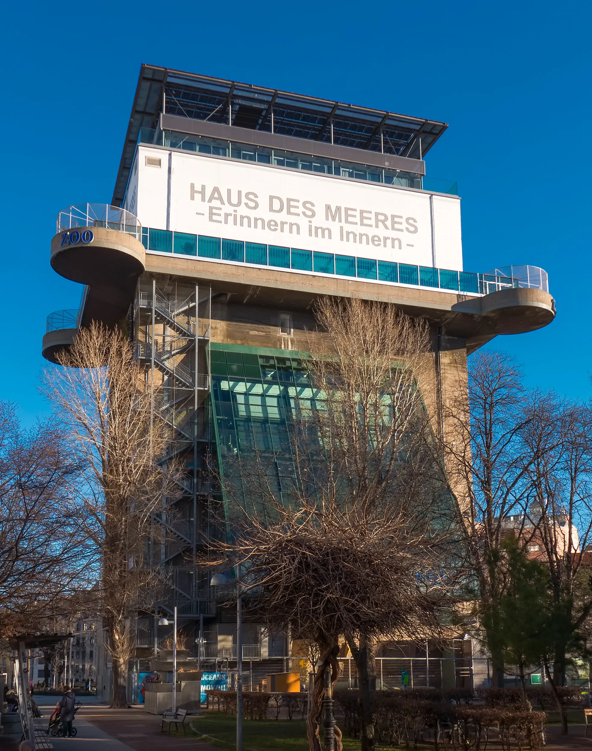 Hoge betonnen toren met een bord met de tekst 'HAUS DES MEERES -Erinnern im Innern-' onder een helderblauwe hemel