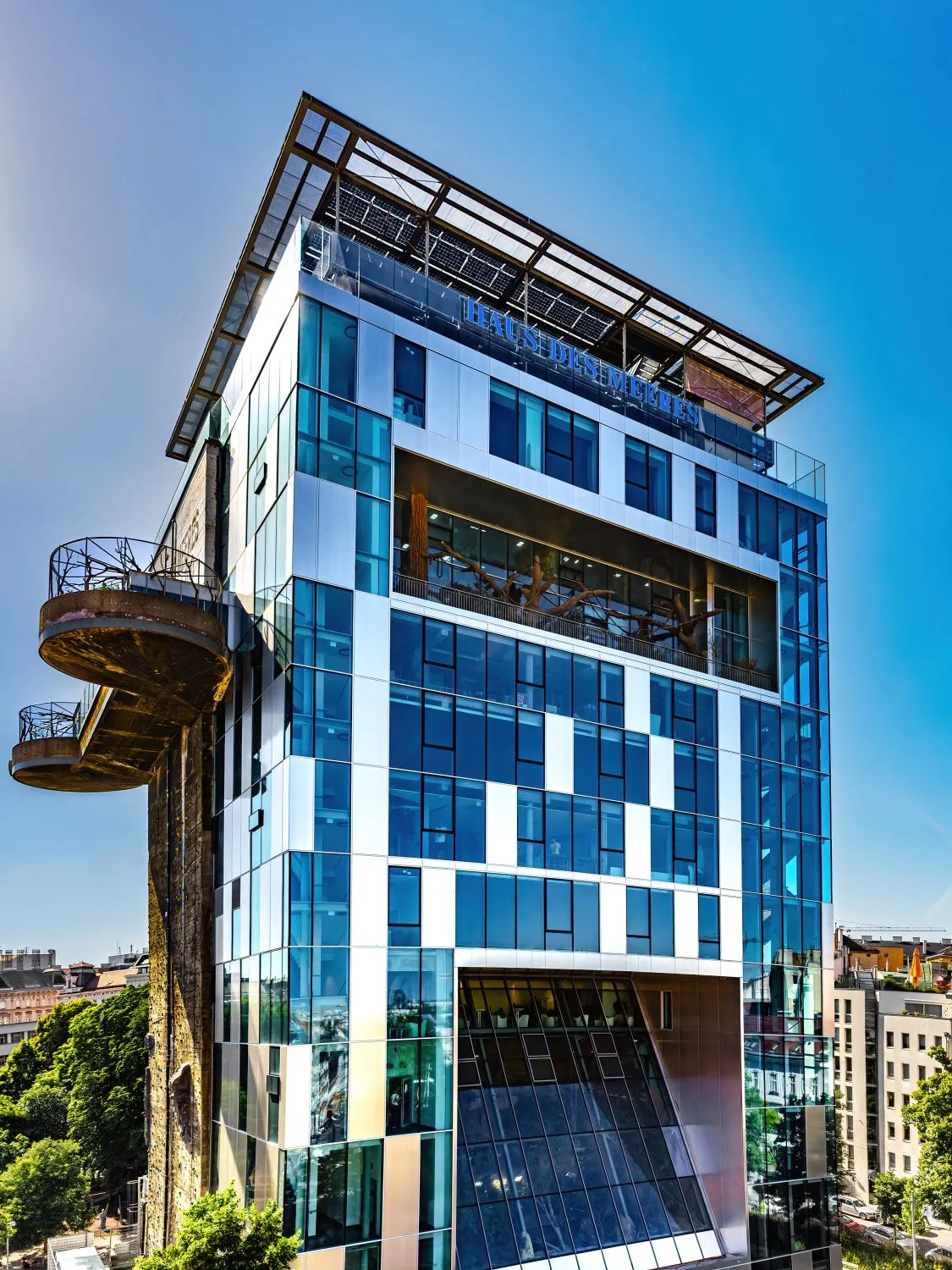 modern glazen gebouw met een dambordpatroon aan de gevel en een gebogen observatiedek dat eraan uitsteekt