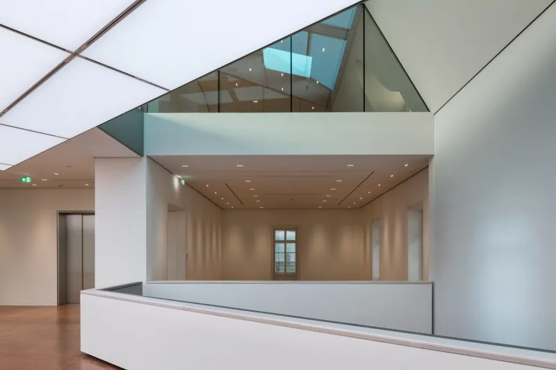 modern interior space with white walls, glass ceiling, and a large open gallery area