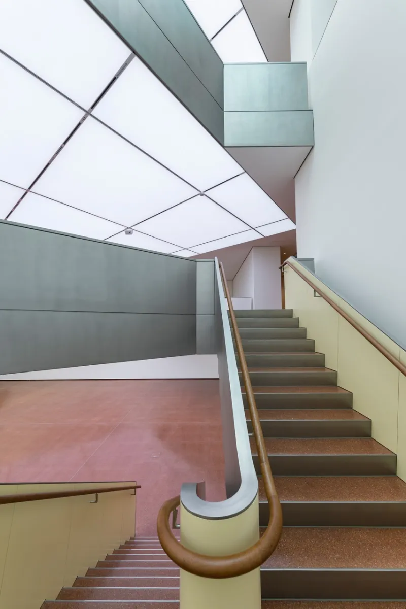 modern staircase with curved handrail and geometric skylight in a museum interior