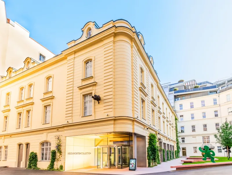 Cream-colored palace building with arched windows and a modern entrance, featuring the Heidi Horten Collection sign