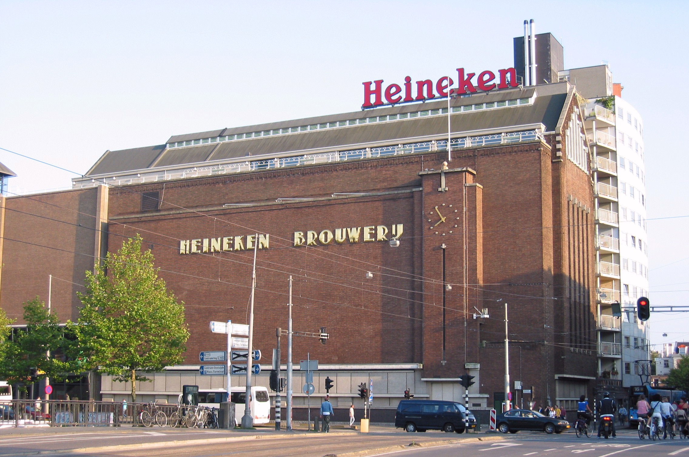 The Heineken Experience building exterior showing the brick facade with 'Heineken' sign and 'Heineken Brouwerij' lettering, located at a city street intersection.
