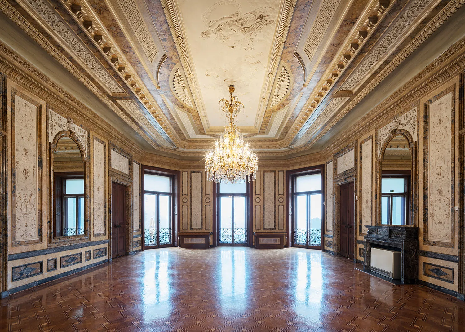 Ornate interior room with gilded ceiling, chandelier, and marble walls
