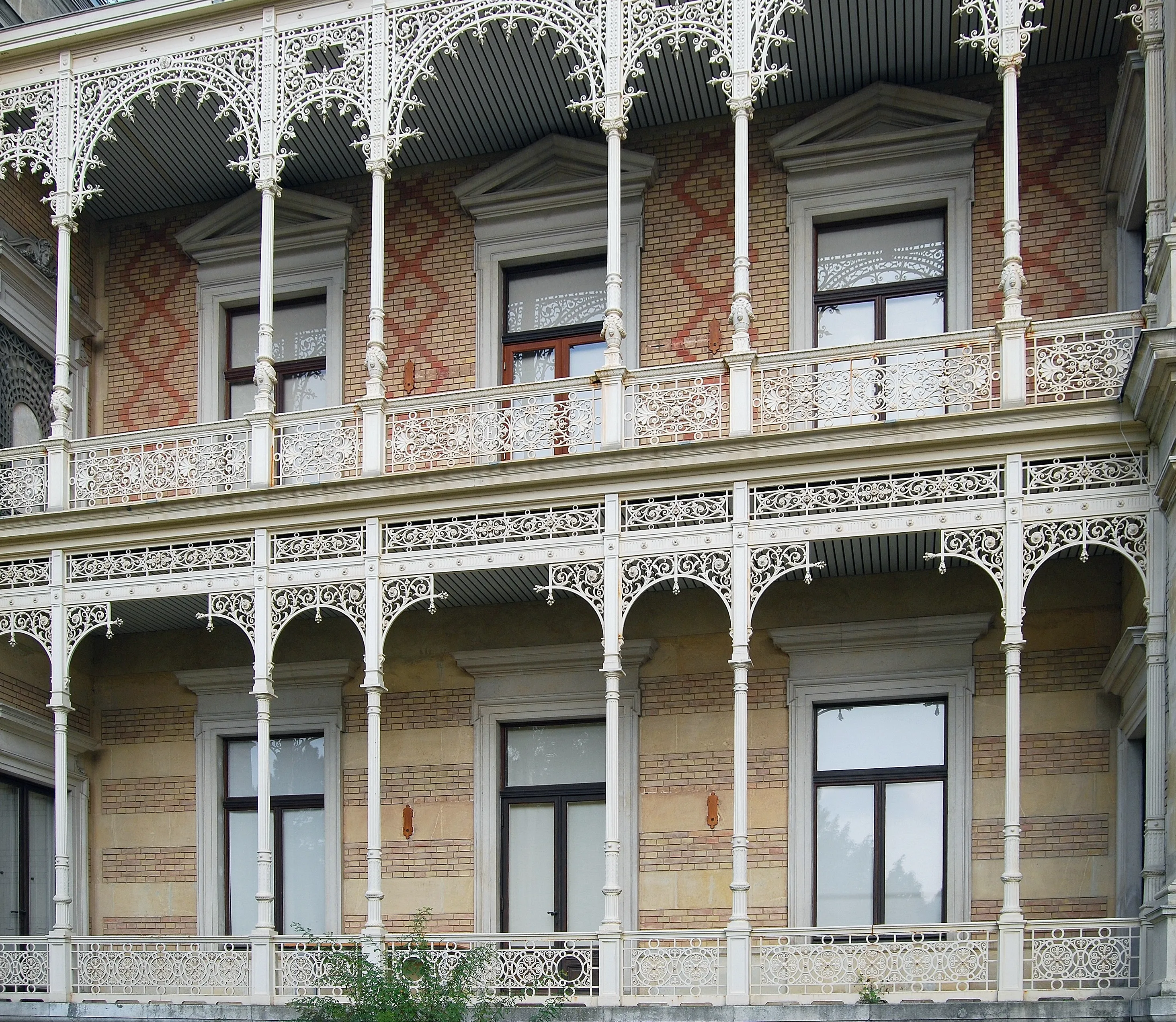 Exterior of Hermesvilla with ornate white iron balconies and patterned brick facade