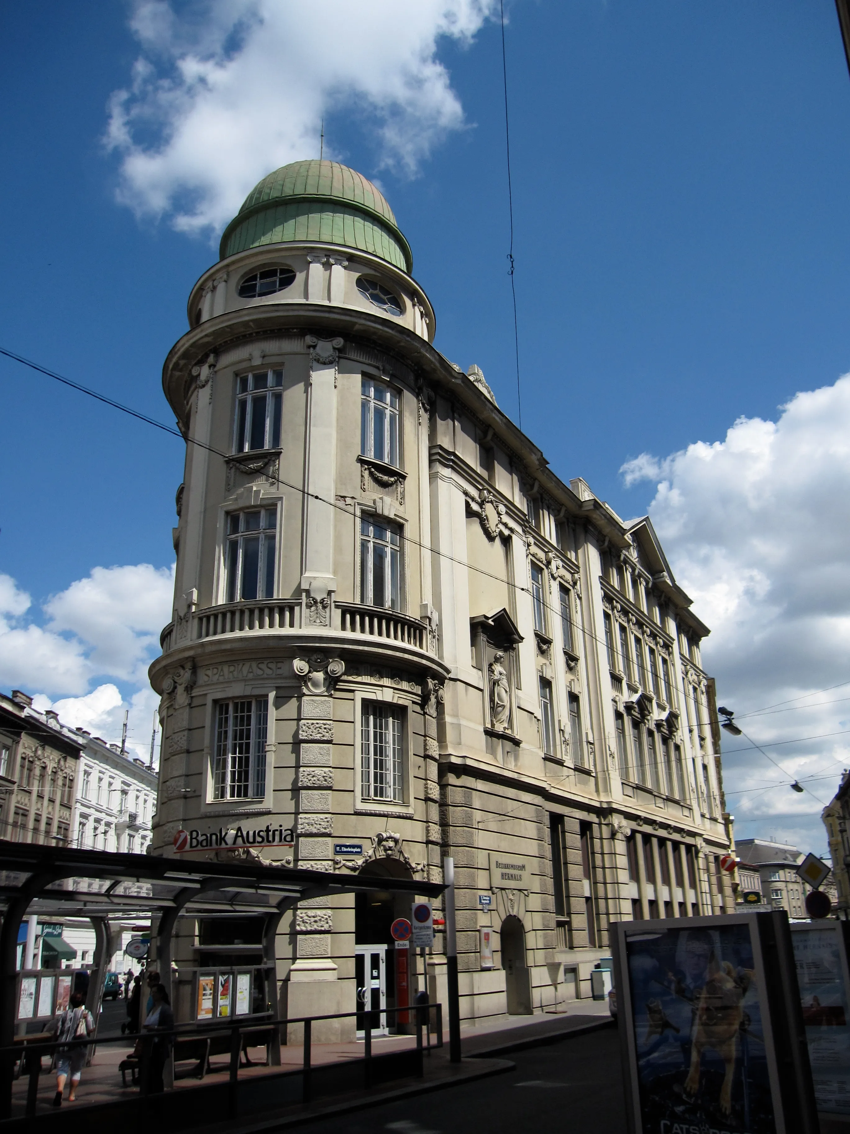 Historisch gebouw met een groene koepel en een sierlijke gevel onder een blauwe hemel
