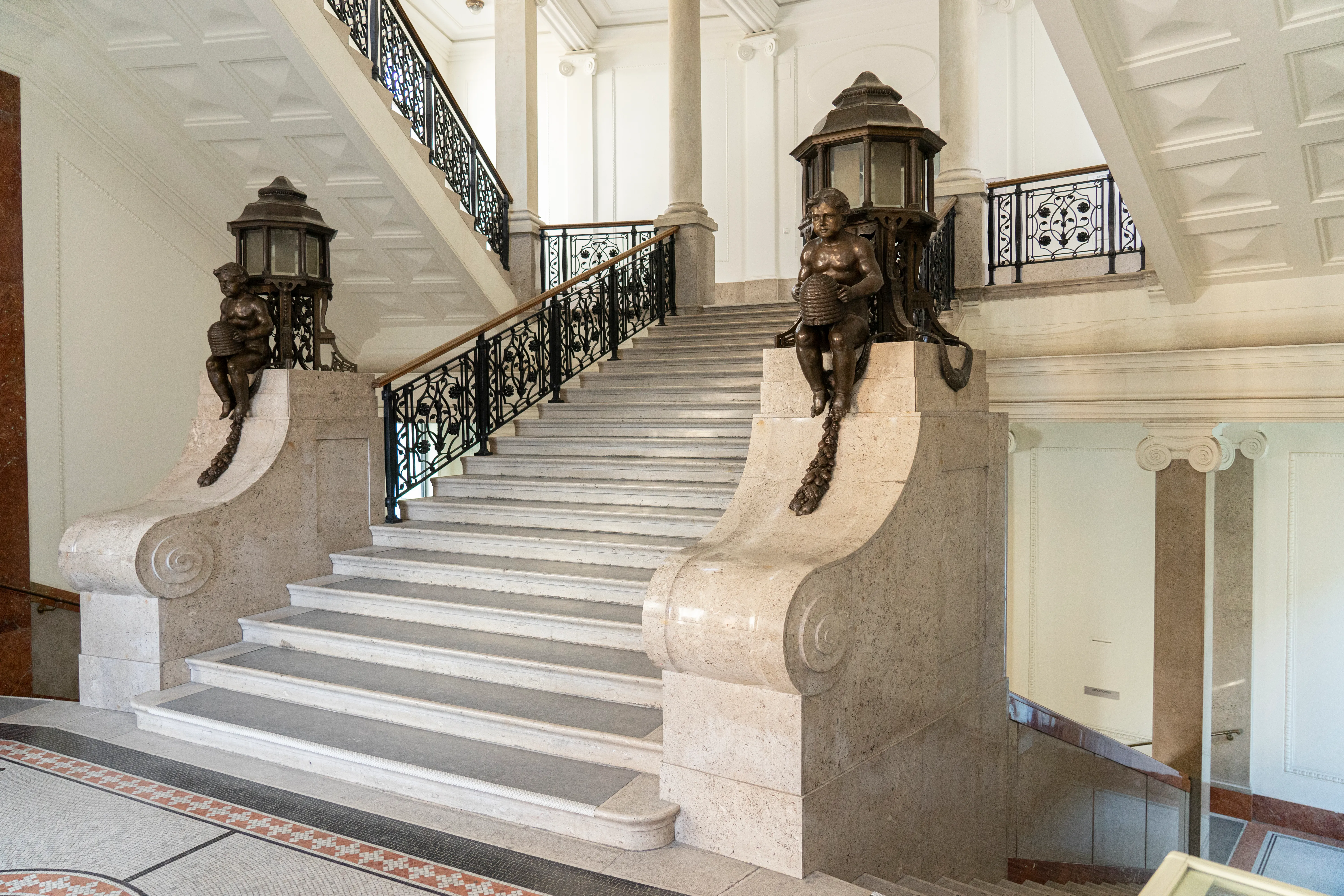 Marmeren trap met sierlijke balustrades en bronzen sculpturen in een museuminterieur