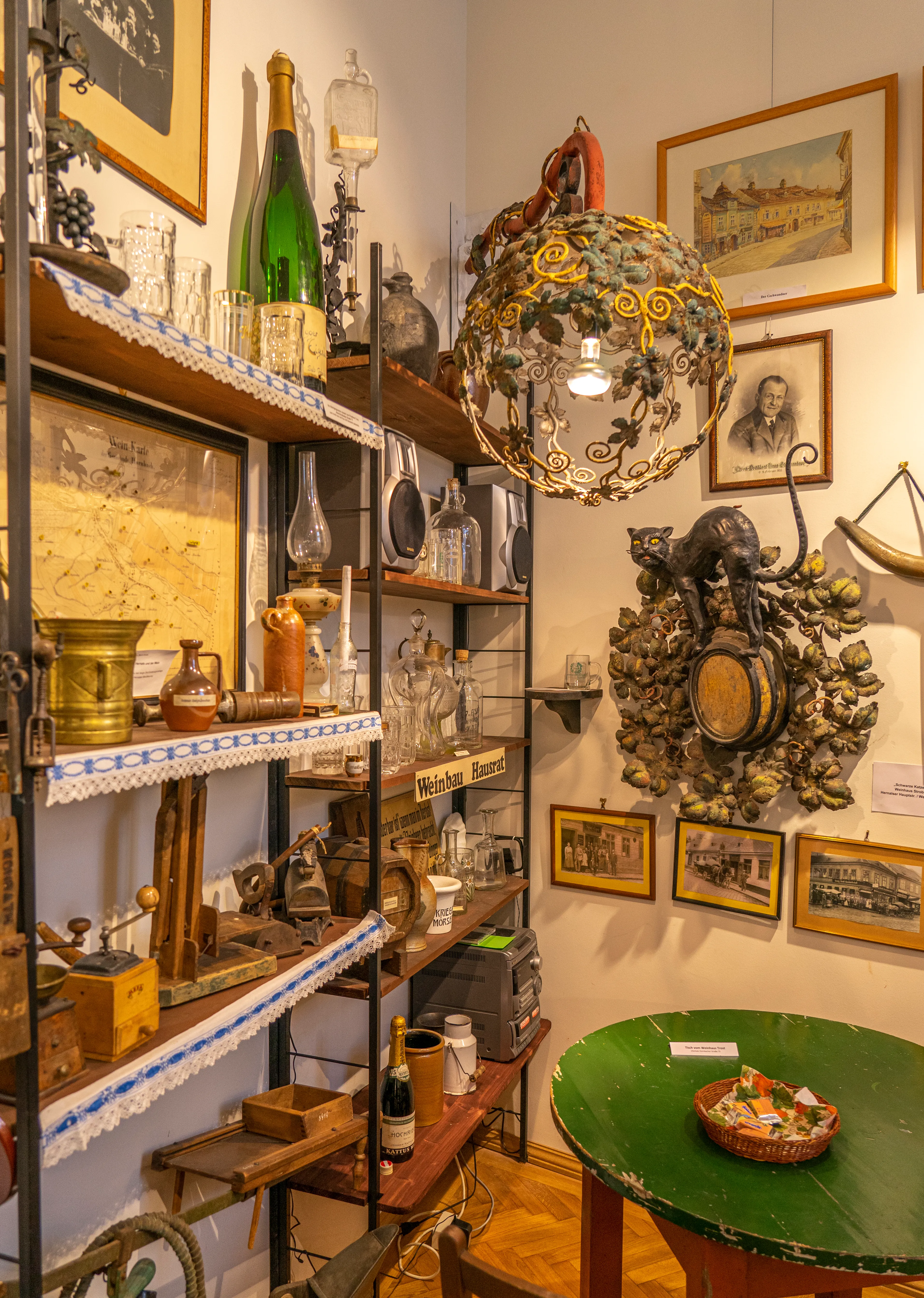 Interieur van het Hernals District Museum met schappen vol artefacten, een decoratieve kroonluchter en ingelijste foto's aan de muur