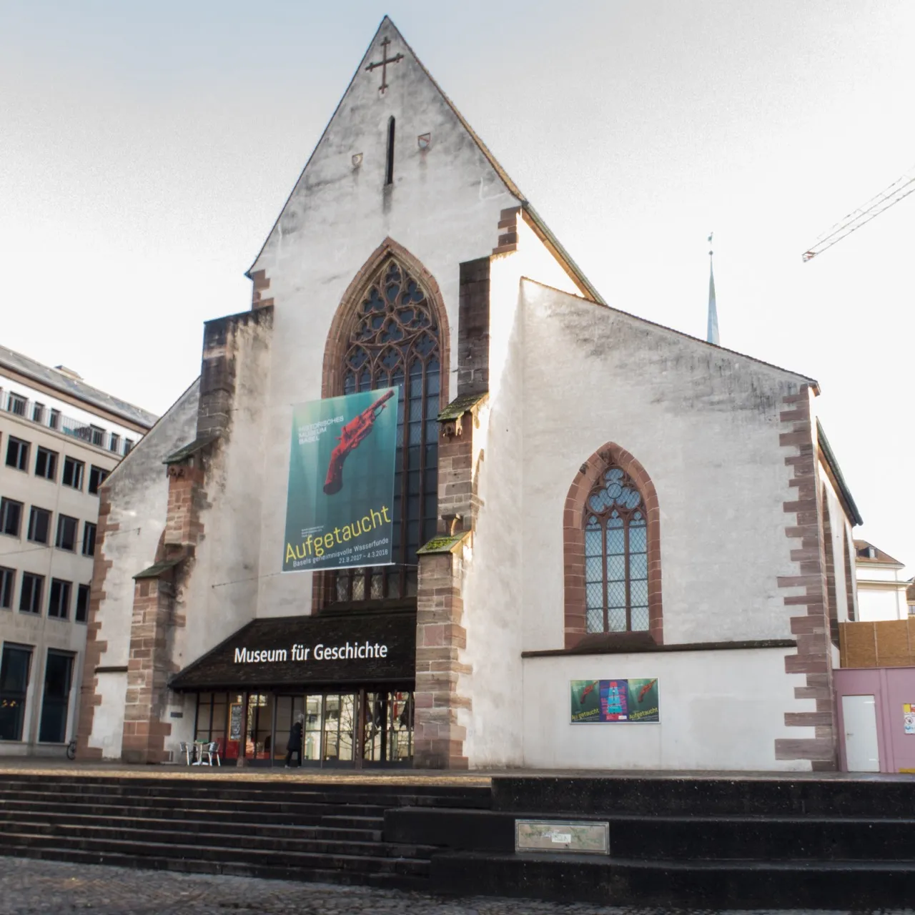Witte trapgevel van de Barfüsserkirche met gotische boogramen, een grote tentoonstellingsbanner en een bord met de tekst Museum für Geschichte boven de ingang