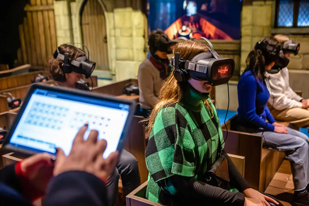 Visitors wearing VR headsets seated in rows at Historium Bruges, with a staff member operating a tablet in the foreground