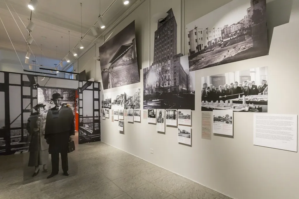 Tentoonstellingsmuur met historische foto's en paspoppen in kleding uit die tijd
