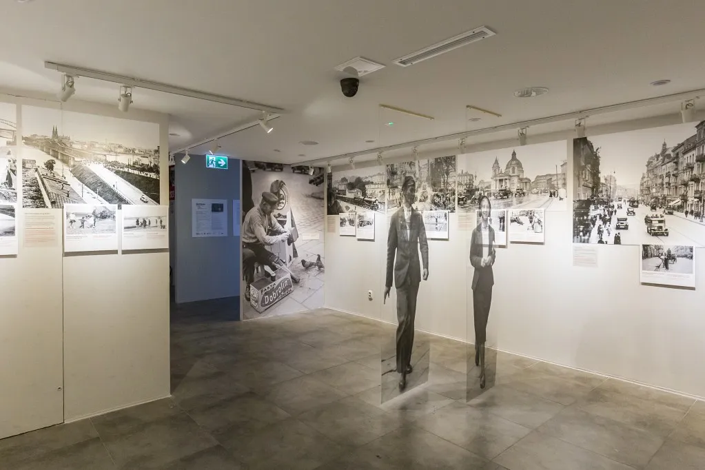 Interieur van een galerie met historische foto's aan de muren en levensgrote uitsneden van mensen