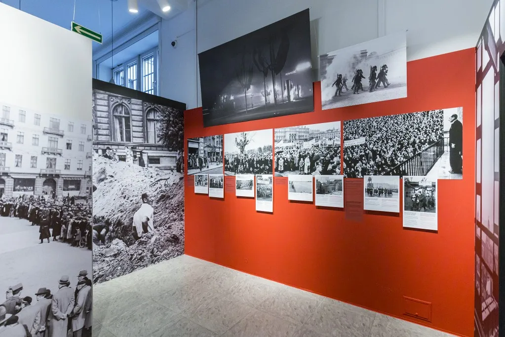 Tentoonstellingsmuur met historische foto's op een rode achtergrond