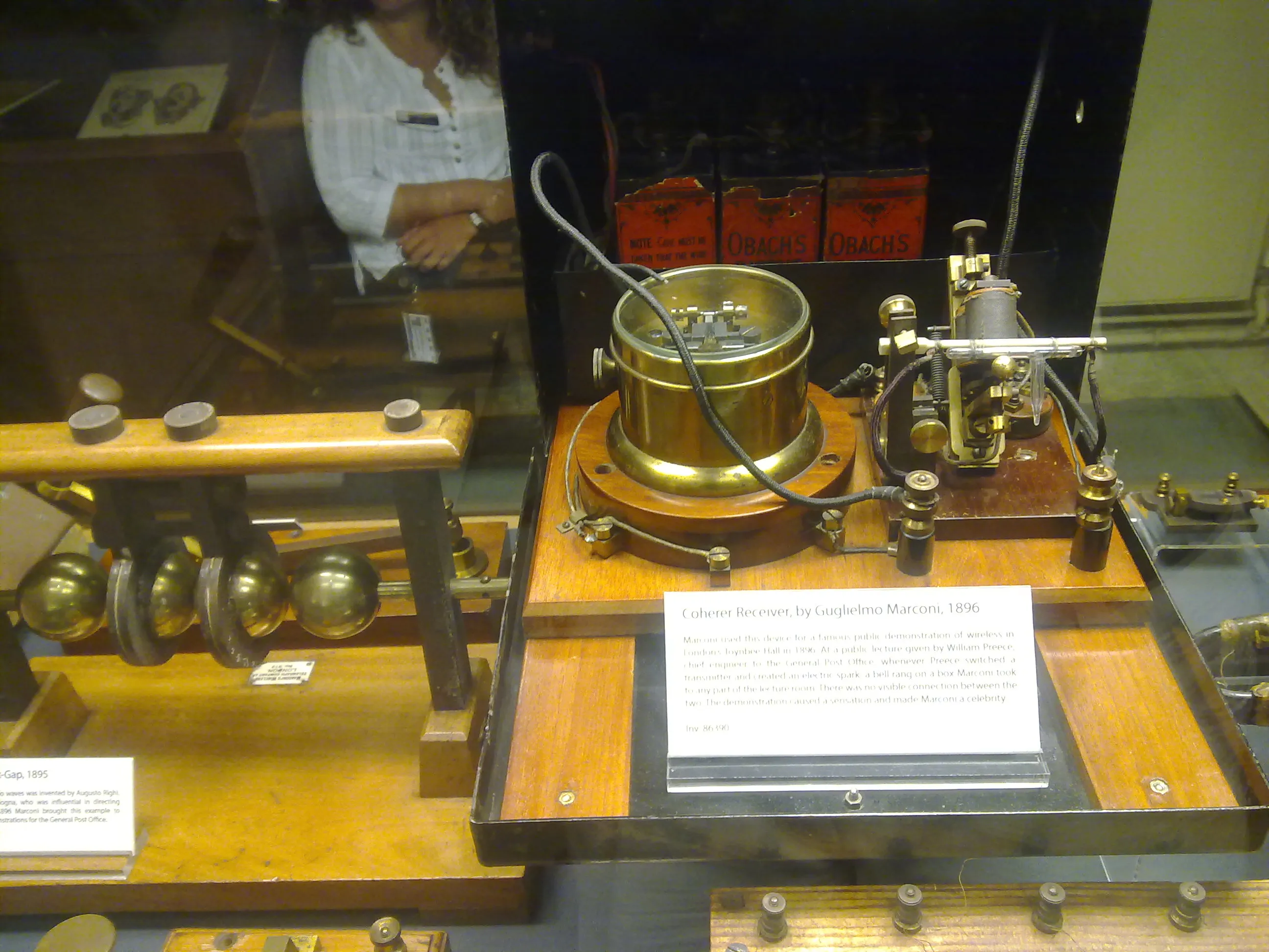 Vitrina de museo que muestra el receptor de coherer de Marconi, un instrumento científico de latón y madera con cables y una placa informativa.