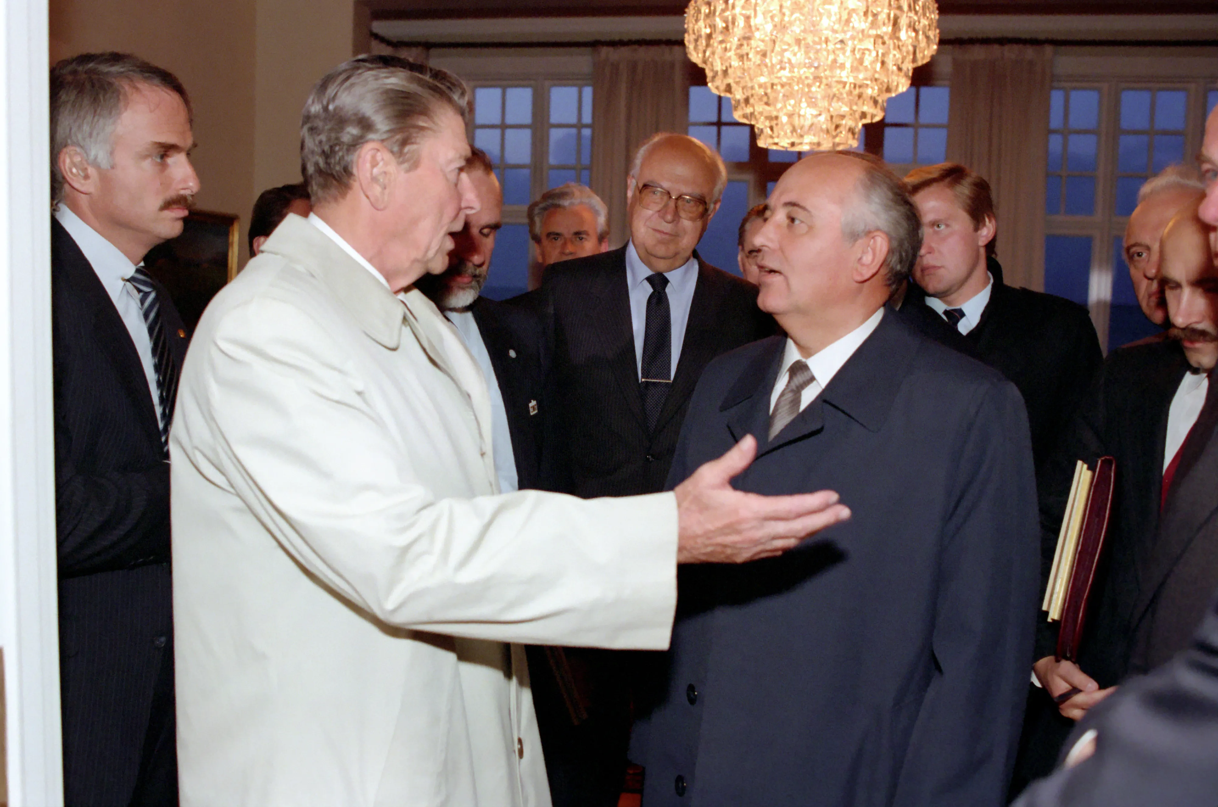 Ronald Reagan and Mikhail Gorbachev talking inside a room with a crystal chandelier at Höfði House.