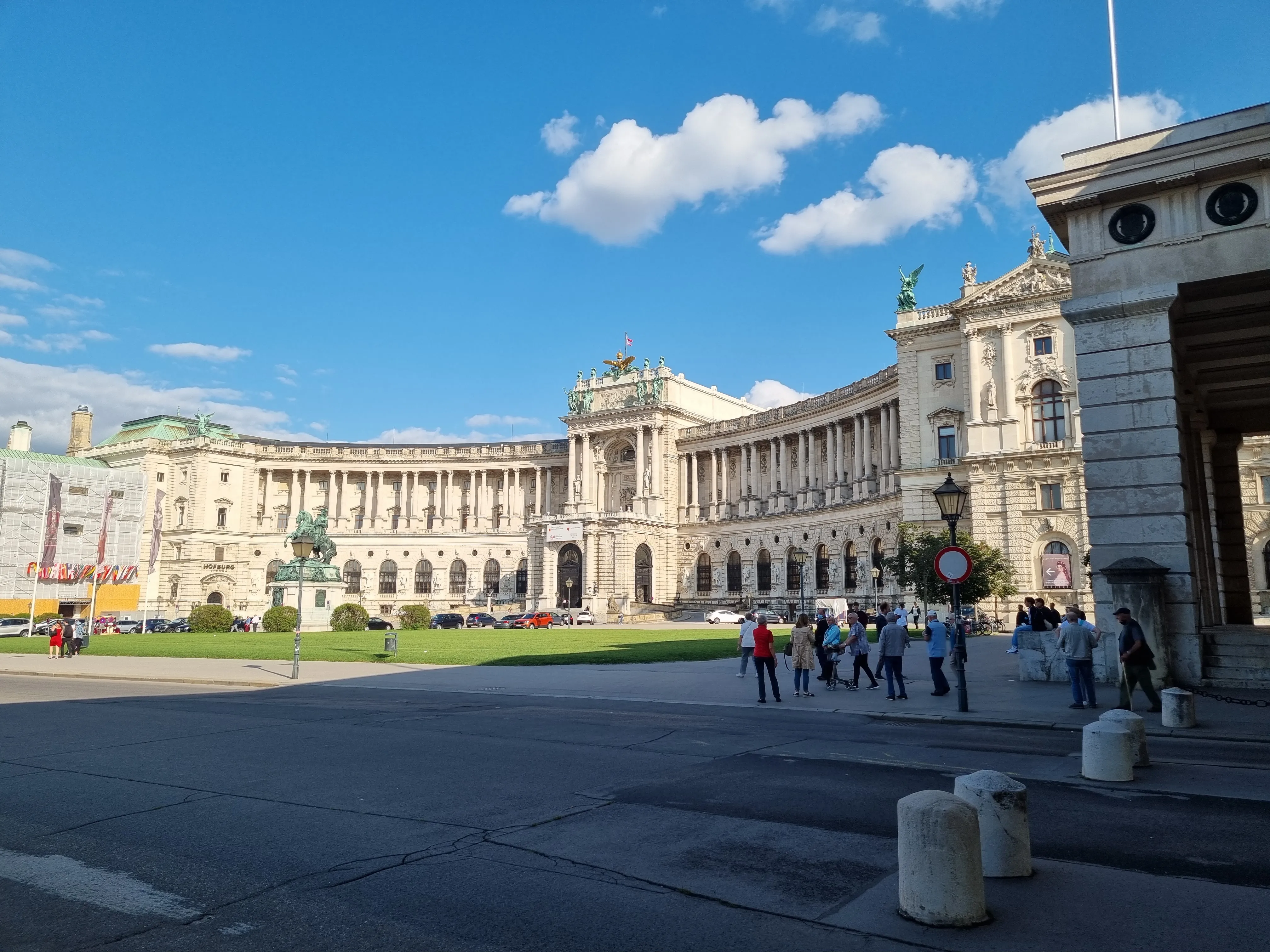 The Hofburg palace with its grand neoclassical facade under a blue sky with white clouds