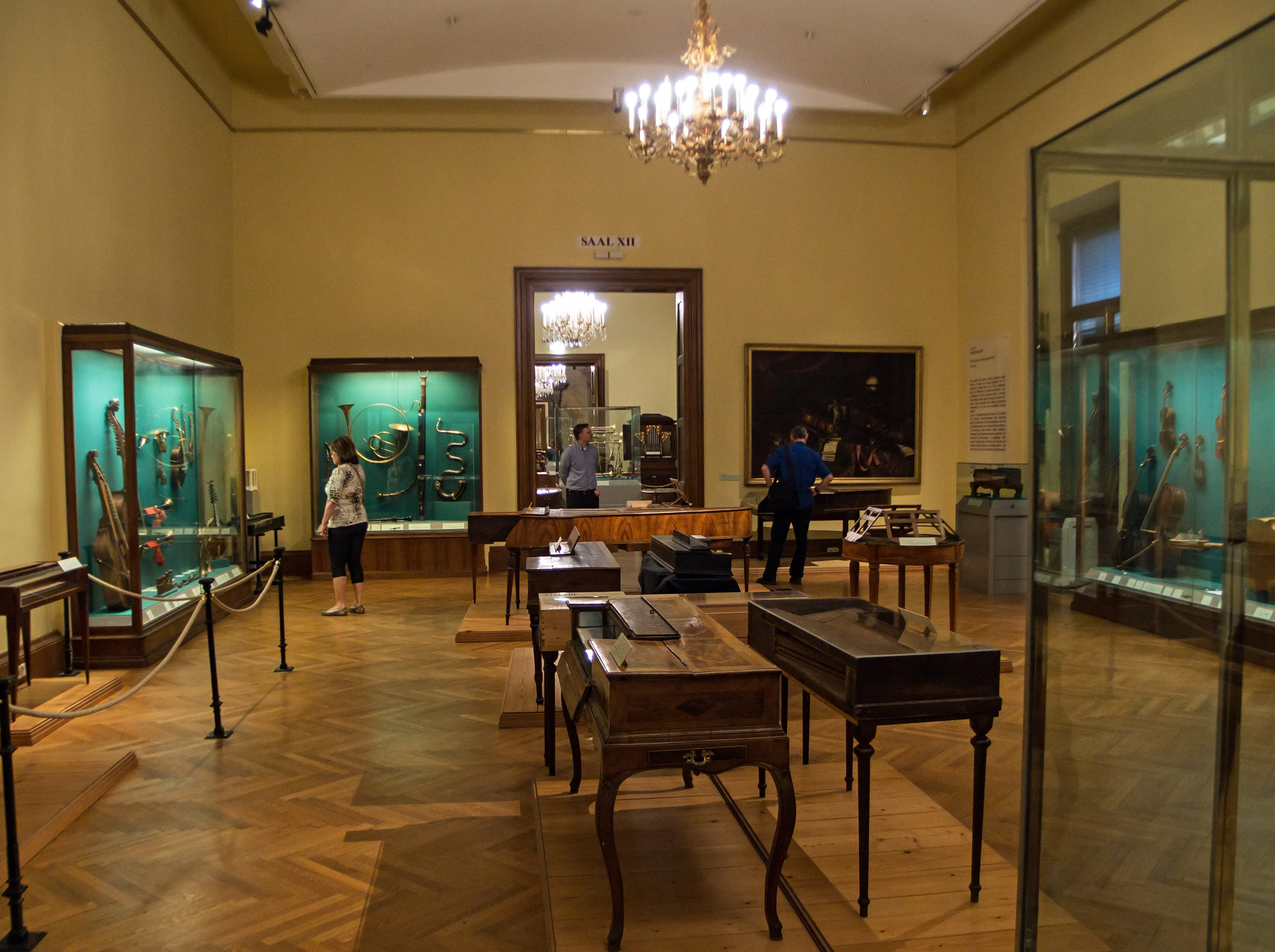 Interior of a museum gallery with wooden display cases, glass exhibits, and a chandelier