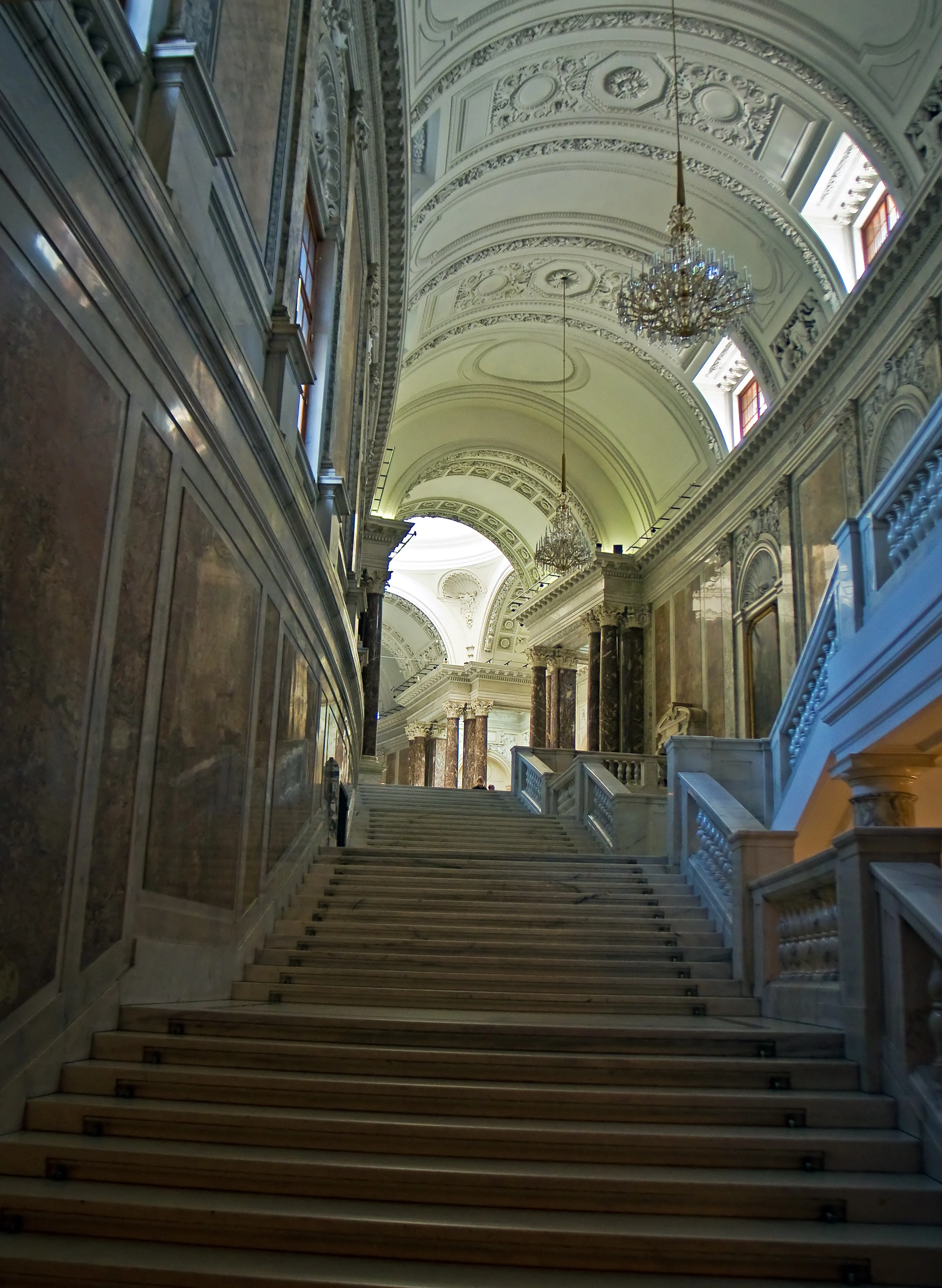 Grand staircase with ornate ceilings and chandeliers inside a historic building