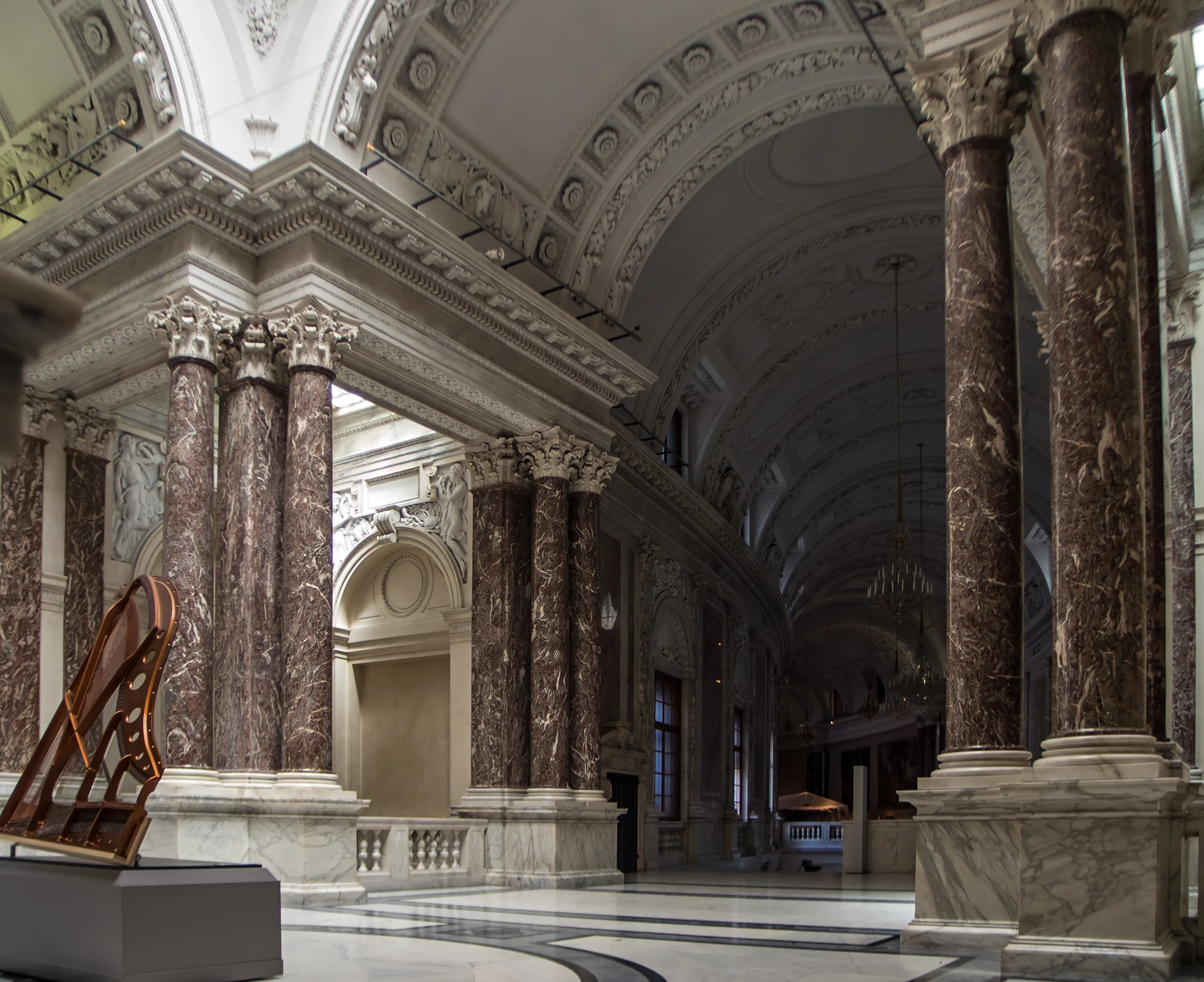 Marble columns and ornate ceiling in a grand hall with a modern sculpture on a pedestal