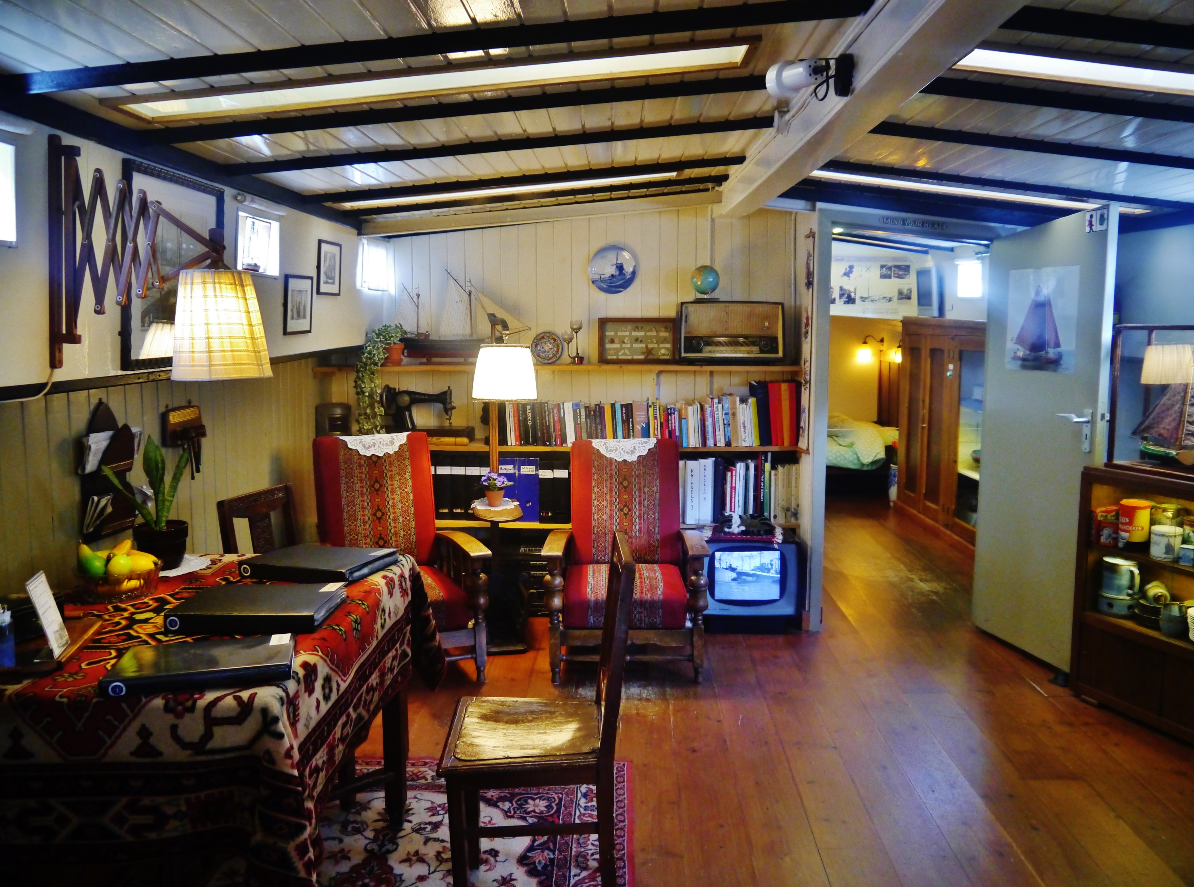 Cozy wooden interior of a canal houseboat museum with bookshelves, patterned textiles, and vintage furniture