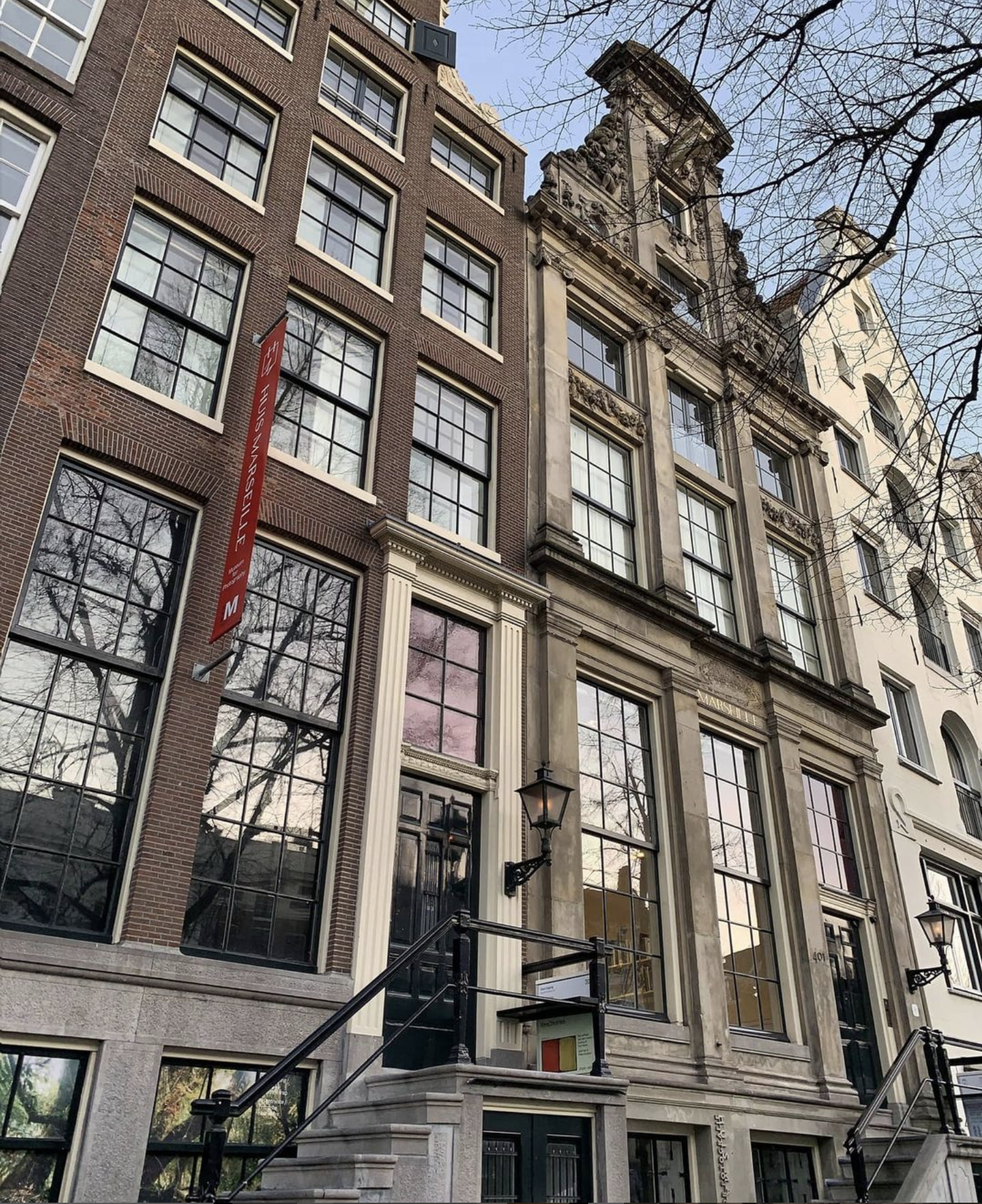 Exterior view of historic Dutch canal houses housing Huis Marseille Museum, featuring tall brick buildings with large windows and distinctive gables.