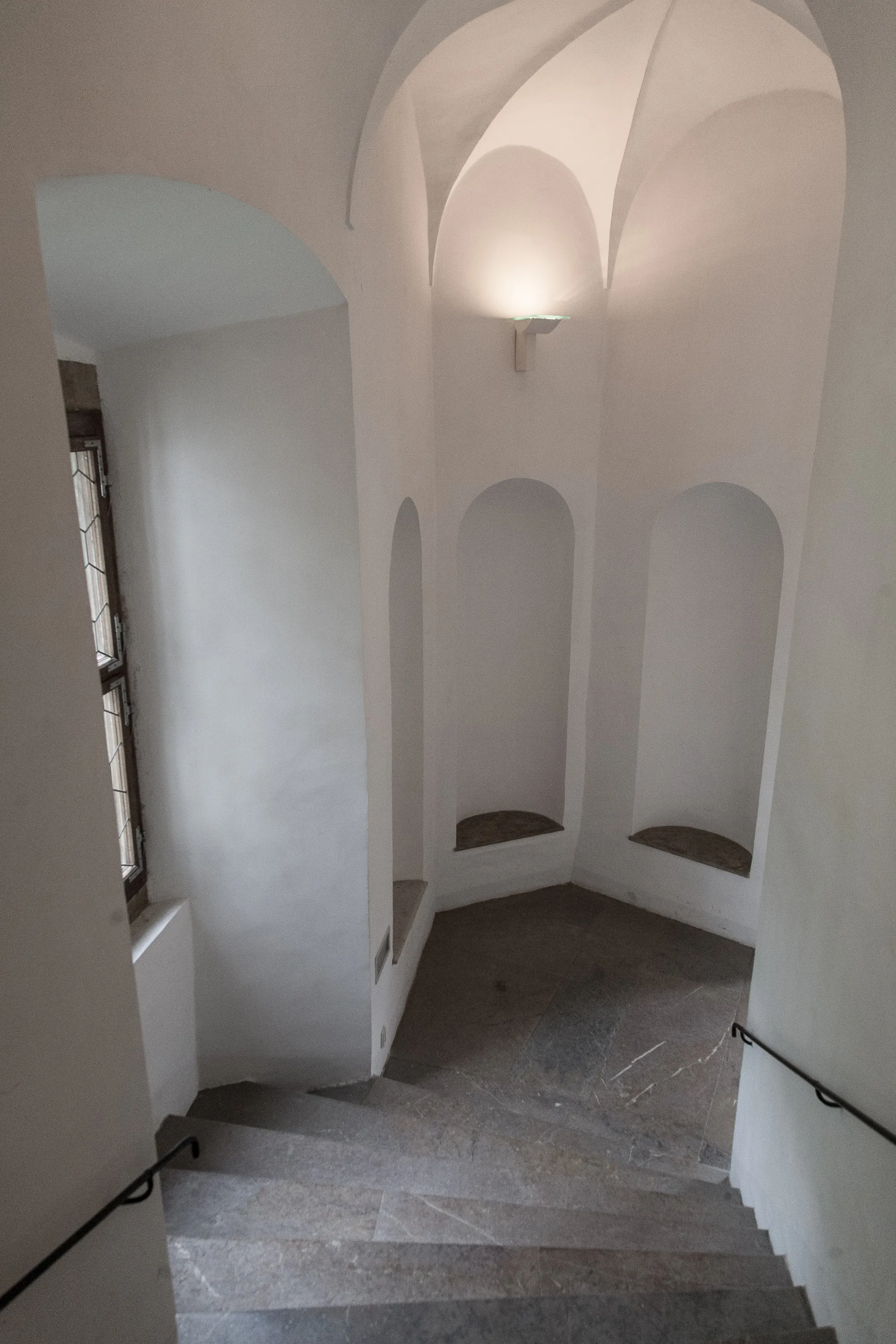 stenen trap met booggewelven en een gewelfd plafond in een wit interieur