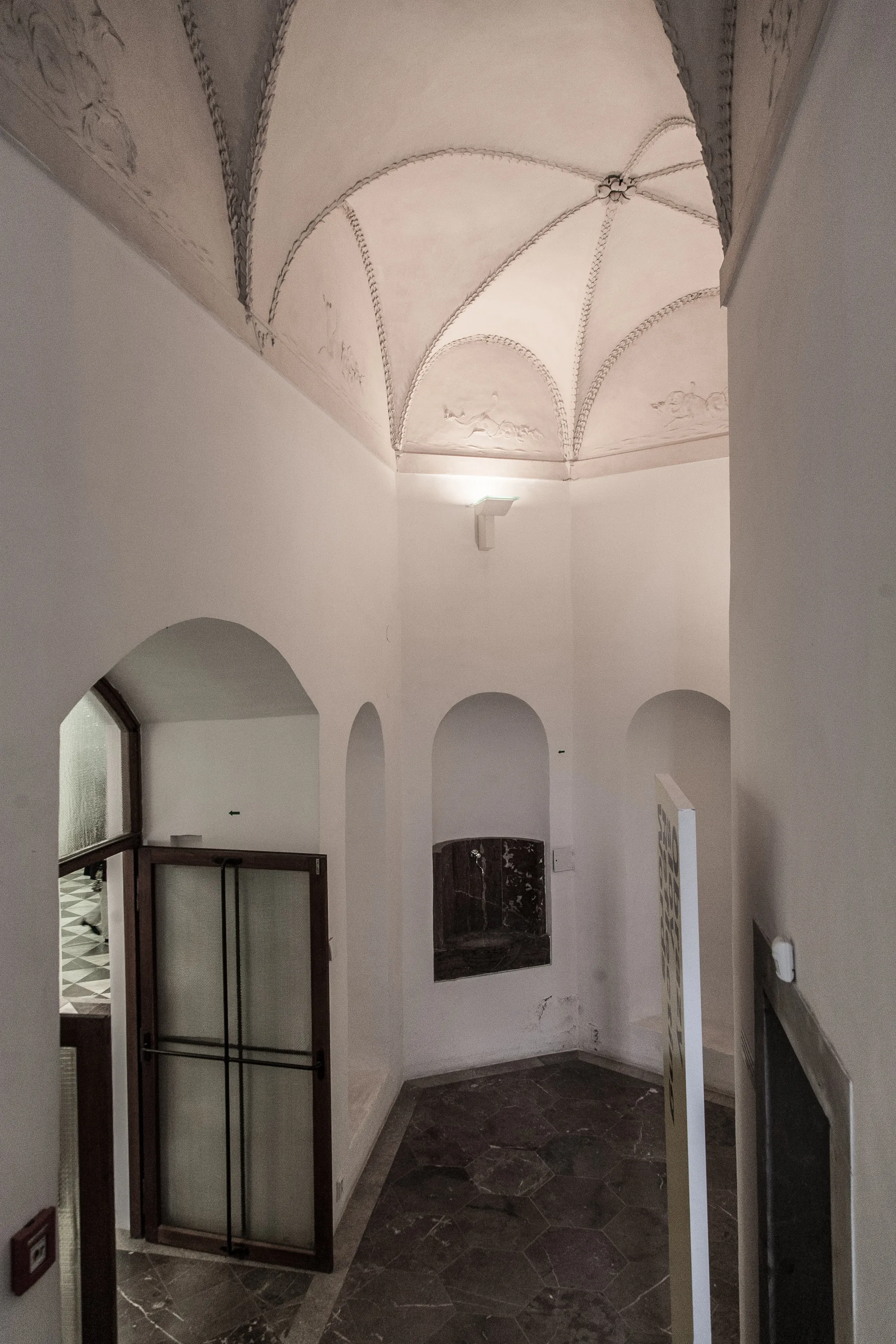 gewelfd plafond met decoratief stucwerk en boogramtes in een wit interieur