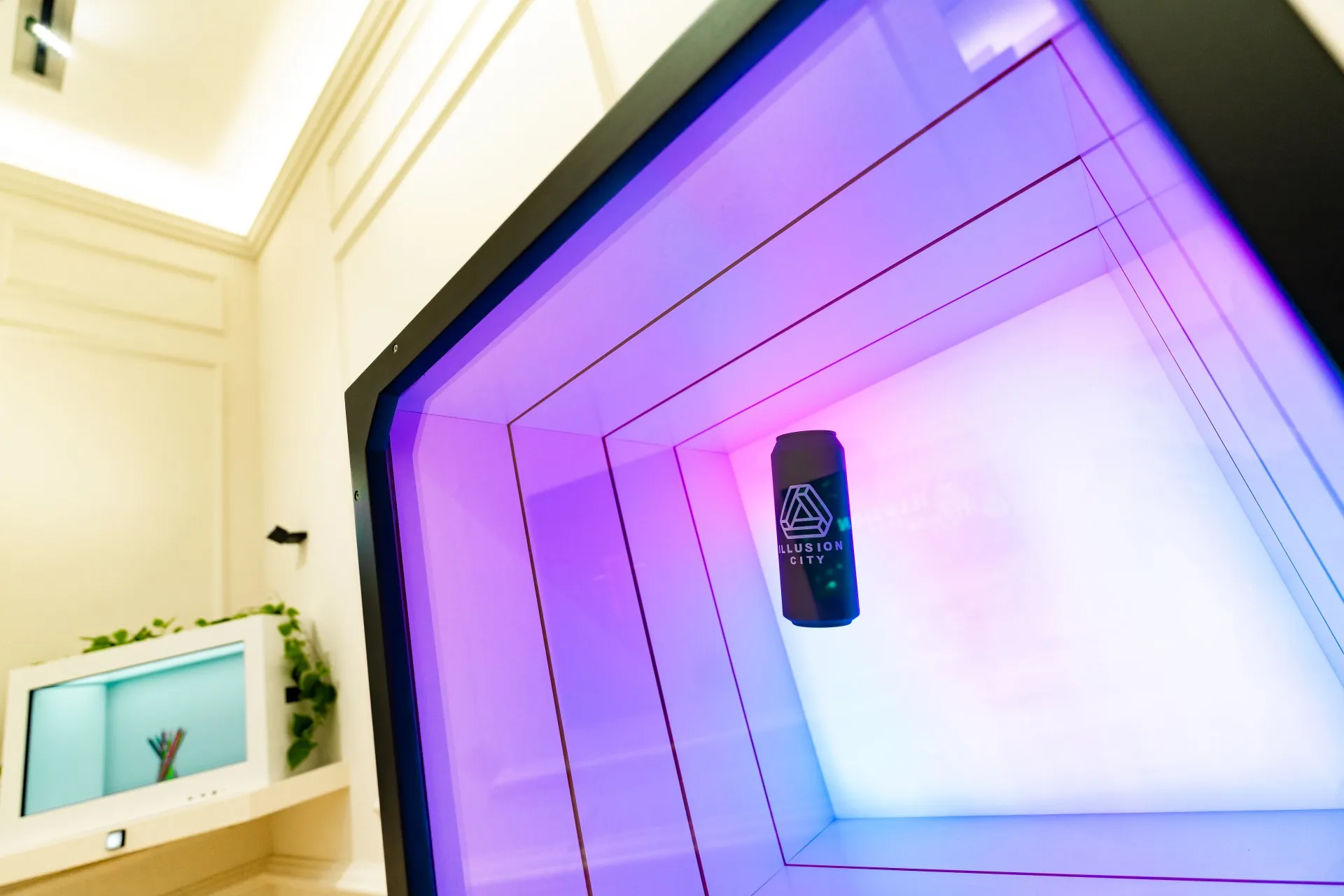 Instalación de túnel iluminado en tonos morados y rosas con el letrero de 'Illusion Antwerpen' colgado en el centro de un interior de museo blanco