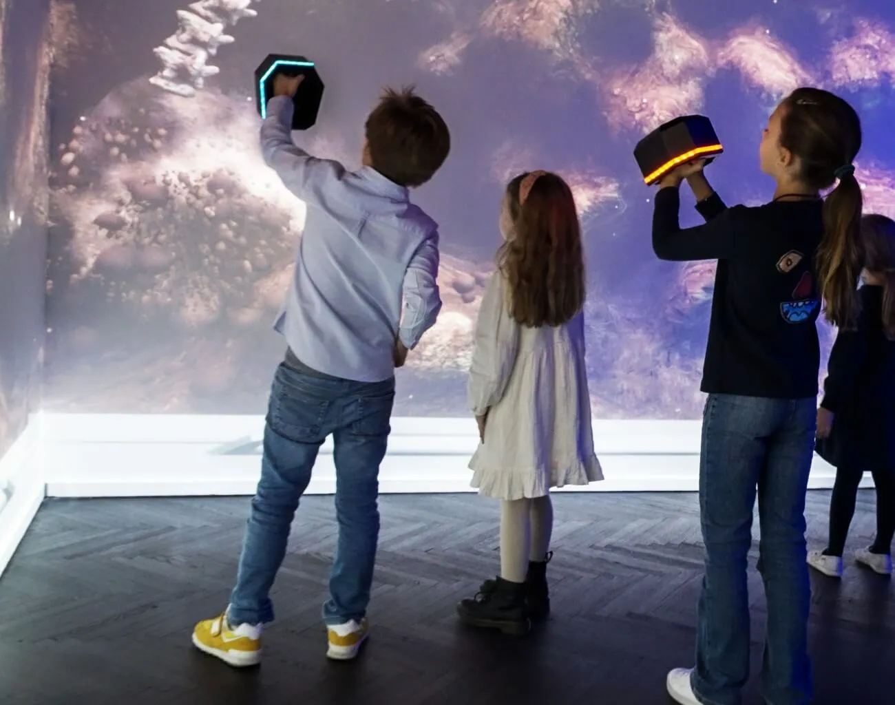 Kinderen die met interactieve apparaten werken voor een grote geanimeerde projectie in Immersium Wenen.