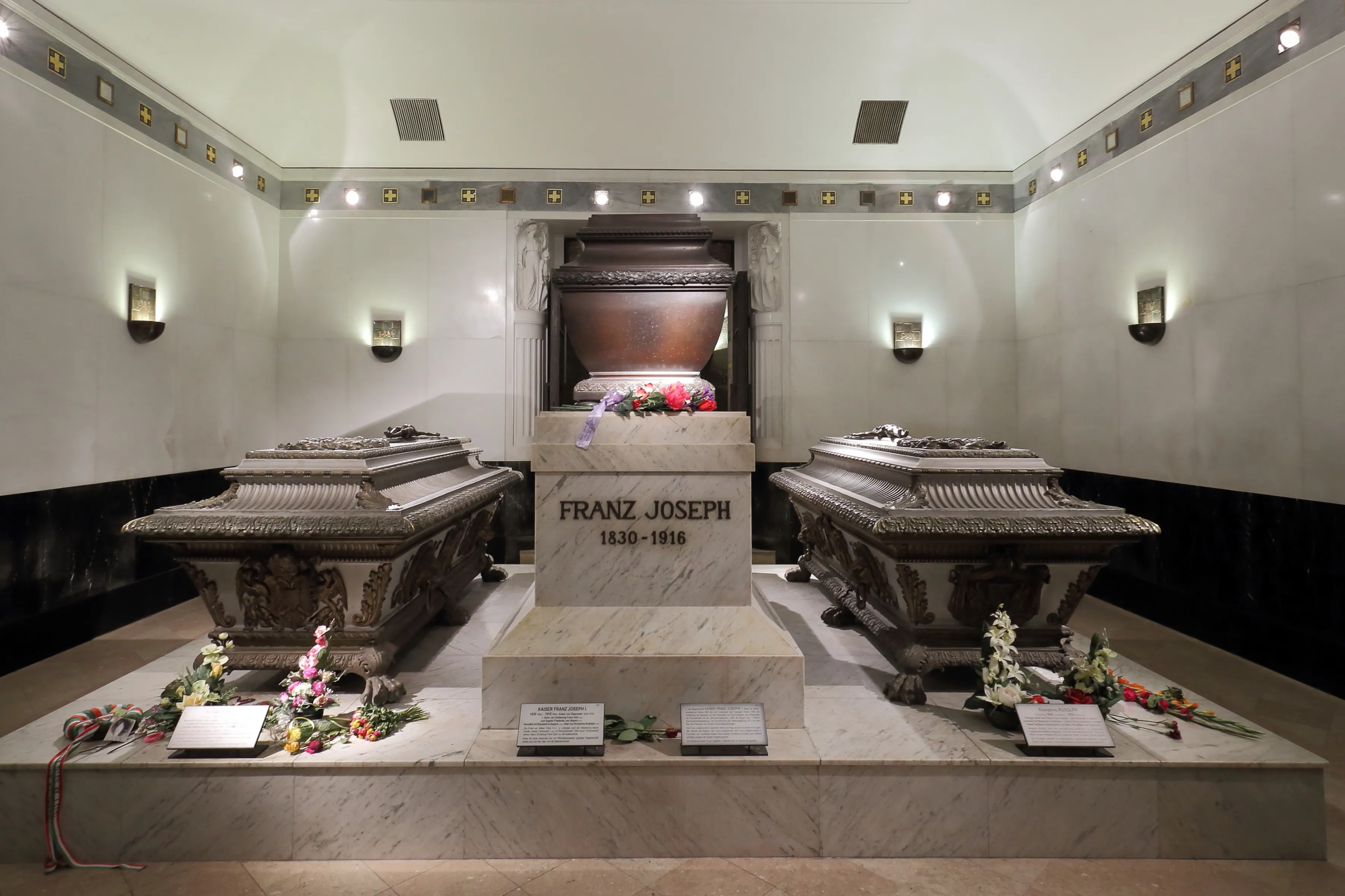 Ozdobne sarkofagi w słabo oświetlonej krypcie z centralnym grobowcem oznaczonym 'FRANZ JOSEPH' i wieńcami